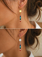 Close-up of earrings with colorful beads worn by a person.