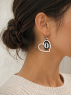 Heart-shaped earring with a football design worn by a person.