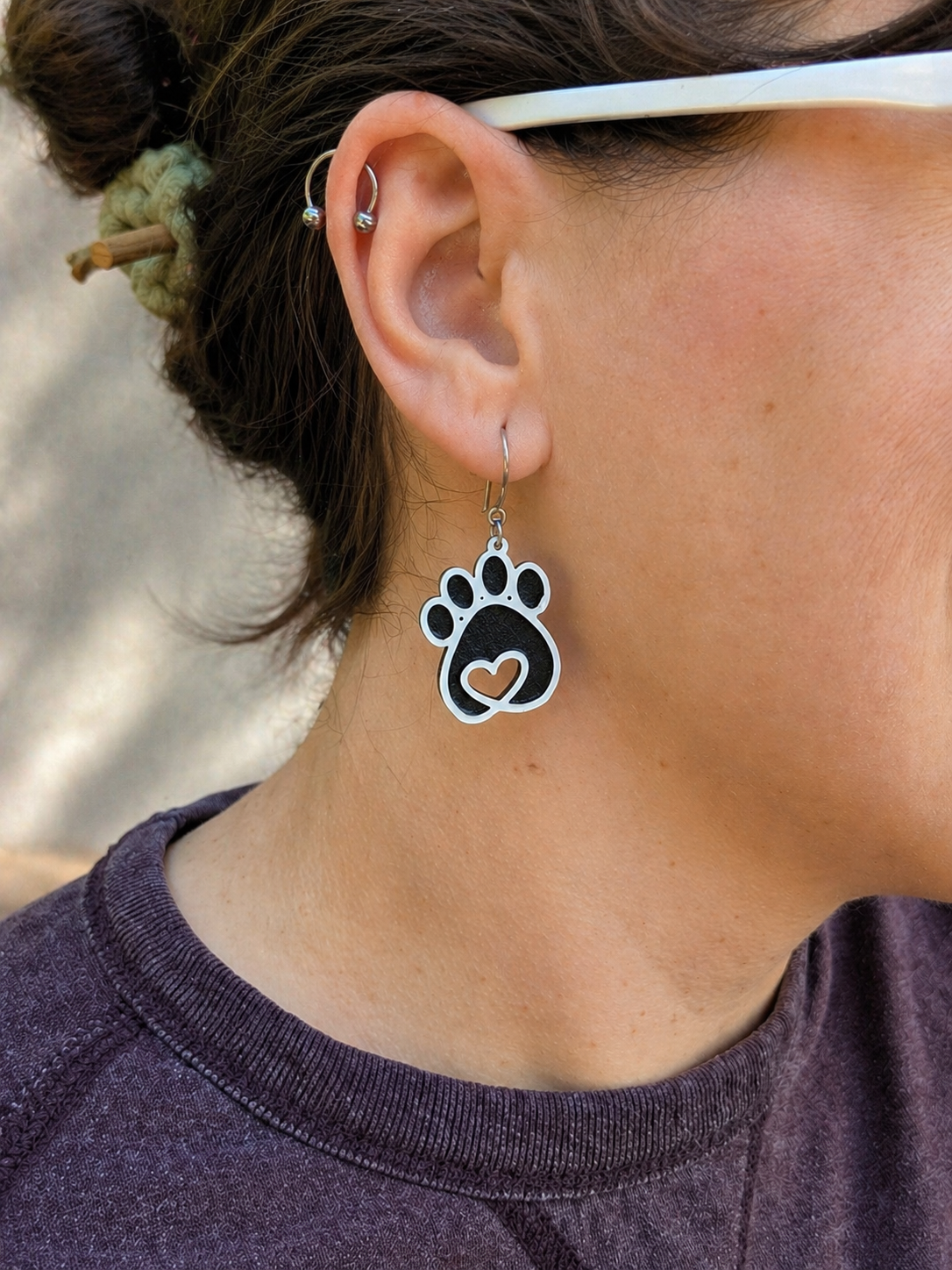 Person wearing a paw print earring with a heart in the center.