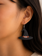 Person wearing a witch hat earring with a neutral background