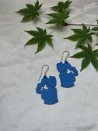 Blue sculpted Lake Tahoe shaped earrings with mountain cutout, silver French hook wires, displayed on white fabric with Japanese maple leaves