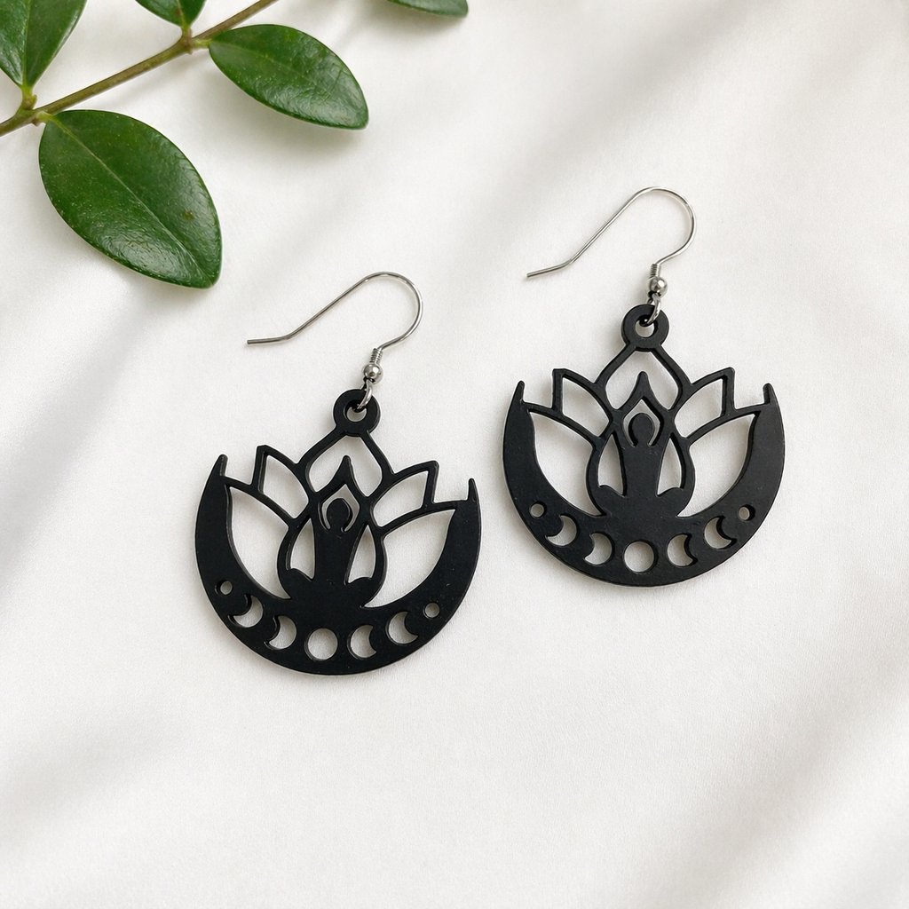 Black lotus flower earrings on a white background with green leaves.