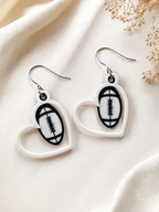 Heart-shaped earrings with football design on a light fabric background