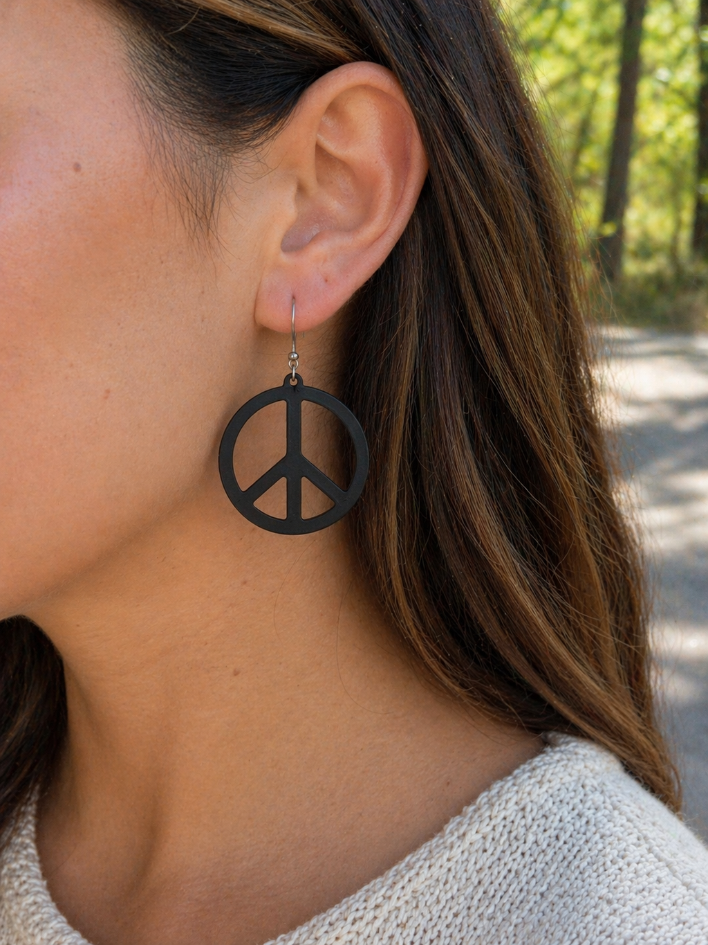 Woman wearing white sculpted peace circle dangle earring outdoors, lifestyle photo, silver French hook, retro boho jewelry