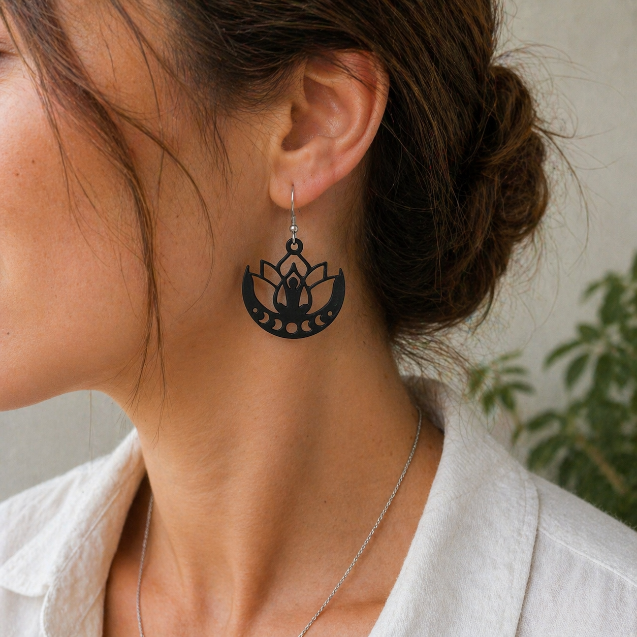 Person wearing a black lotus flower earring with a blurred background