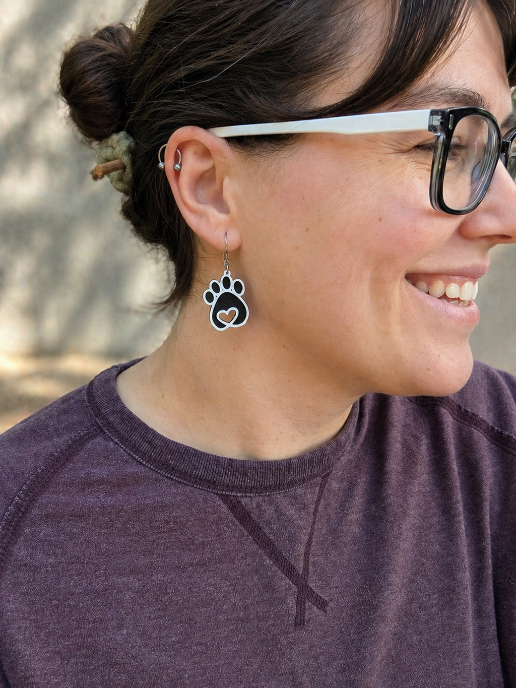 Person wearing paw print earrings with a blurred natural background