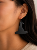 Black whale-shaped earrings worn by a person with a neutral background
