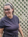 Woman wearing a gray macramé braided headband with adjustable elastic back, styled in a half-up hairstyle