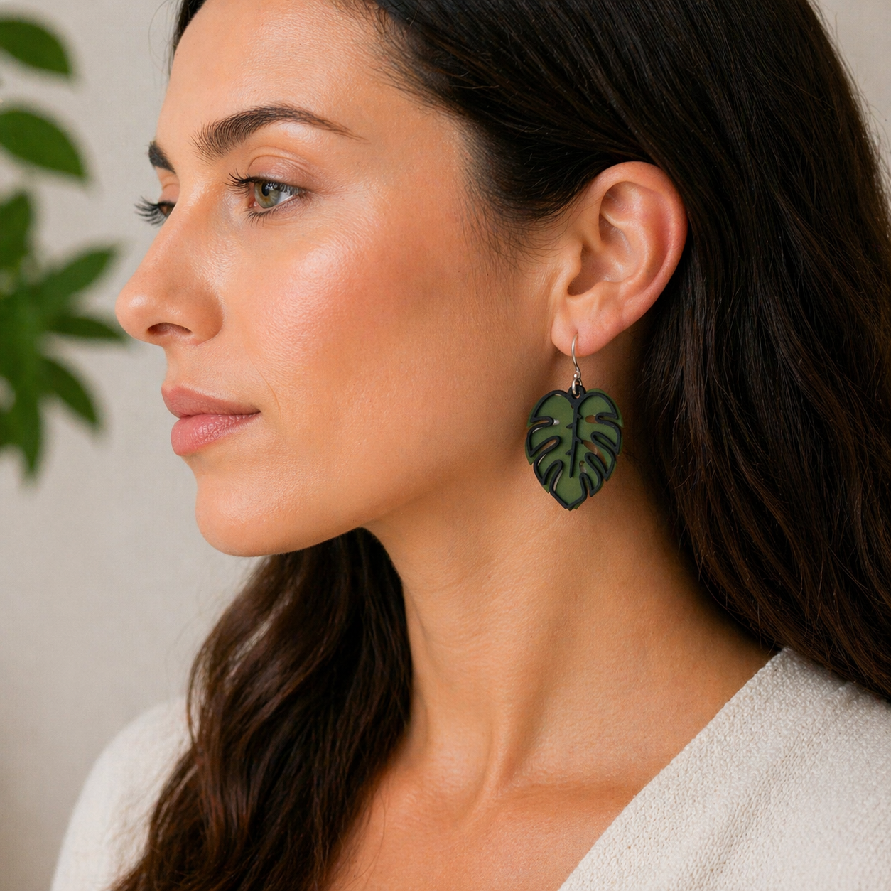 Side profile of woman wearing green monstera leaf earrings with black outline detail, sculpted botanical jewelry